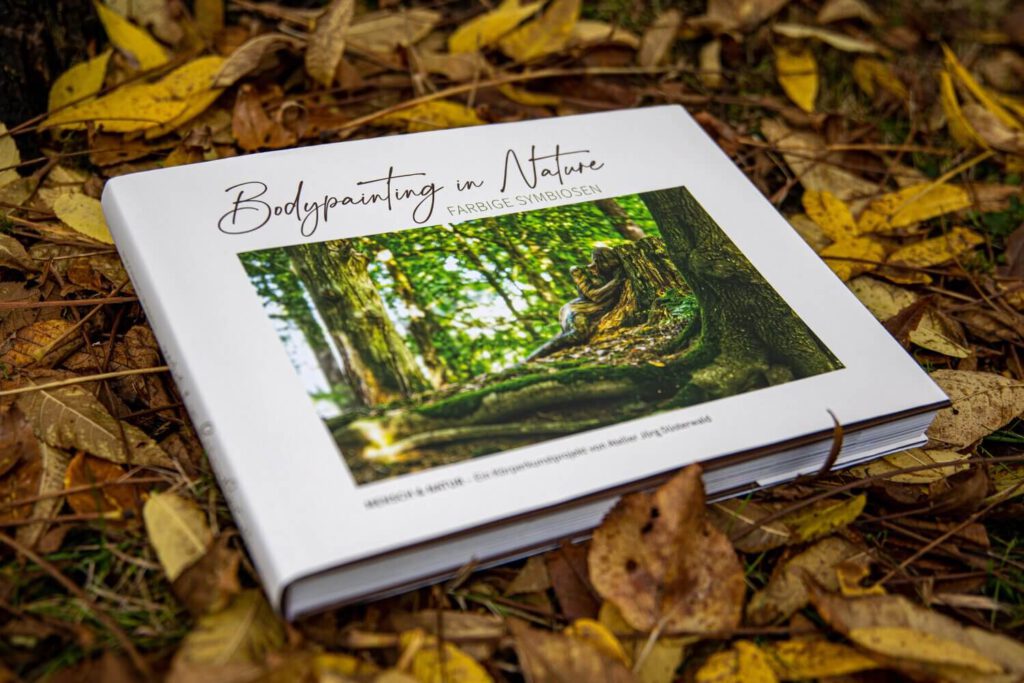 Künstler Jörg Düsterwald hat von dem Körperkunstprojekt Nature Art einen Fotobildband publiziert. Das Buch liegt geschlossen in Laub