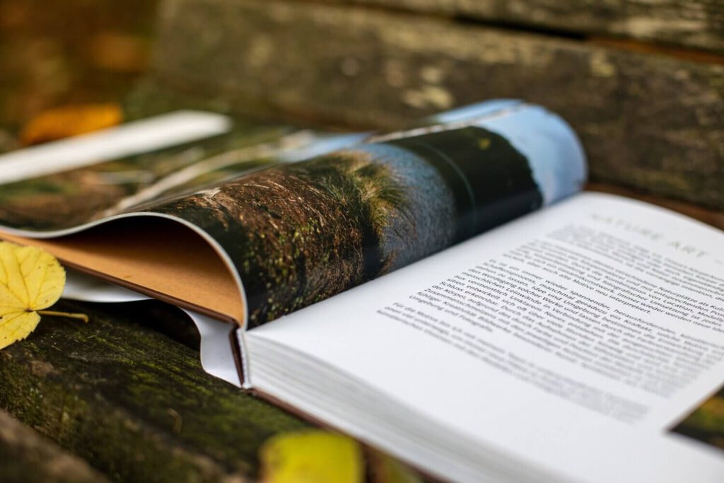 Künstler Jörg Düsterwald hat von dem Körperkunstprojekt Nature Art einen Fotobildband publiziert. Das Buch liegt aufgeschlagen auf einer Bank.