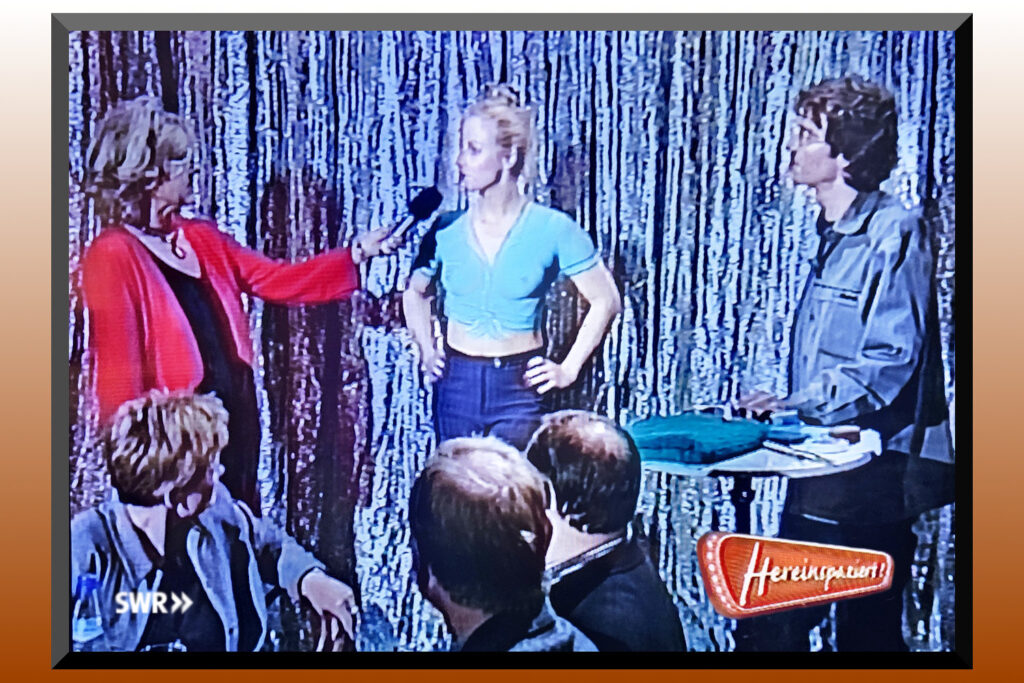 Das am Oberkörper unbekleidete und von Künstler Jörg Düsterwald bemalte Fotomodell wird während einer Fernsehsendung von Moderatorin Siggi Harreis interviewt.