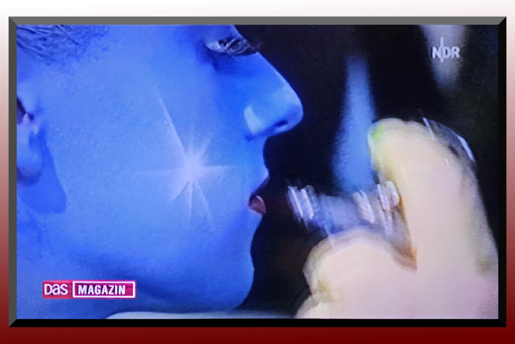 Ein Fotomodell wird von Künstler Jörg Düsterwald im Gesicht mit blauer Farbe besprüht.