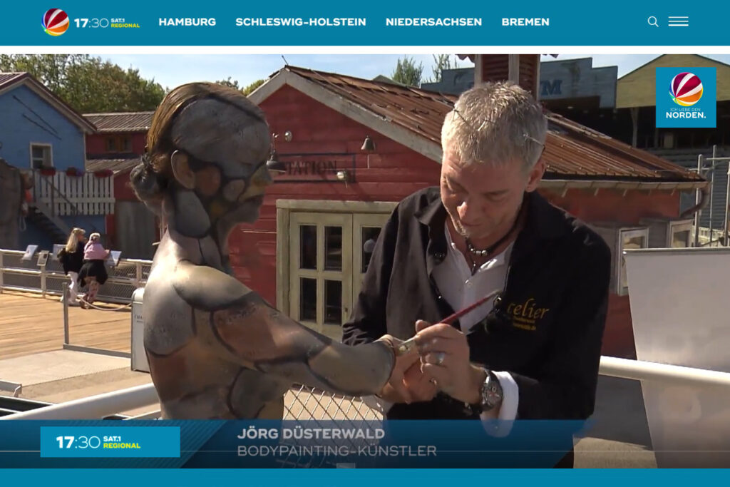 Künstler Jörg Düsterwald bemalt ein nacktes Fotomodell mit einem Steine-Muster.