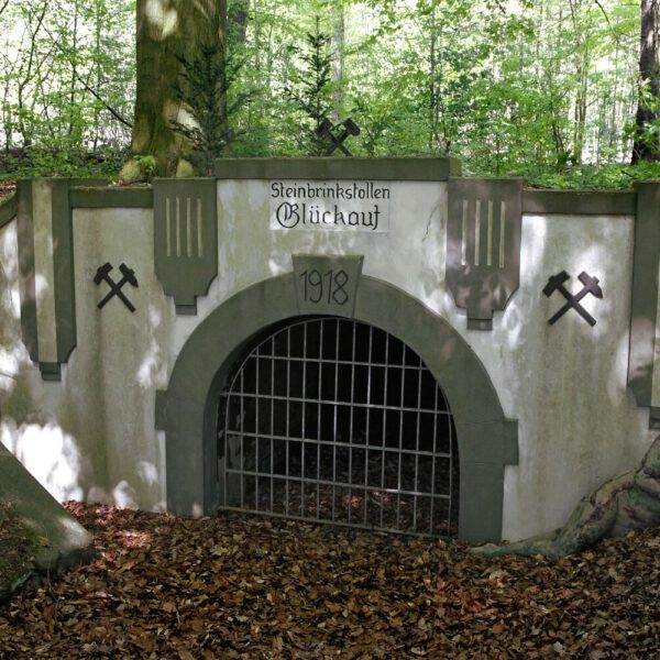 Für das Kunstprojekt DOOR ART ließ sich ein nacktes Fotomodell von Künstler Jörg Düsterwald vollständig so mit Farbe bemalen, dass es genau zur Umgebung von Türen und Toren passt. Die Frau liegt neben dem Eingang zu einem Bergwerkstollen.