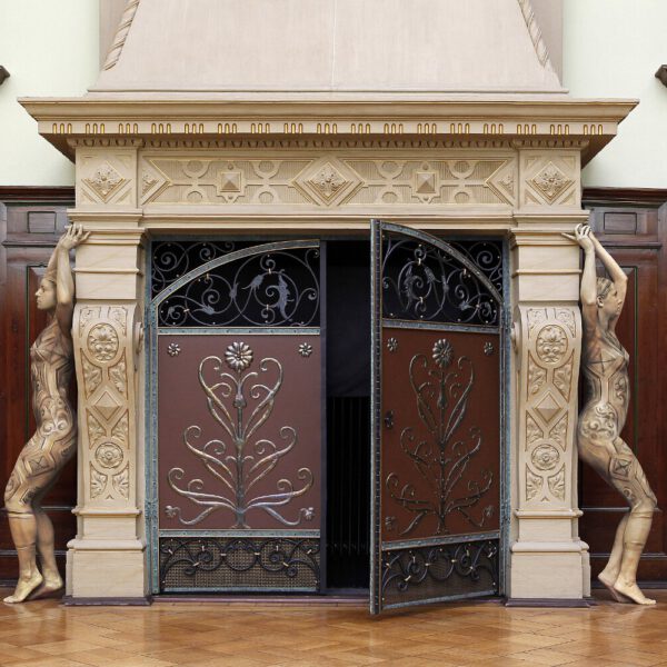Für das Kunstprojekt DOOR ART ließen sich zwei nackte Fotomodelle von Künstler Jörg Düsterwald vollständig so mit Farbe bemalen, dass sie genau zur Umgebung von Türen und Toren passen. Sie stehen wie Steinskulpturen links und rechts neben einem großen Kamin.
