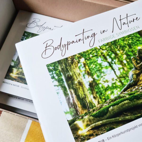 Künstler Jörg Düsterwald hat von dem Körperkunstprojekt Nature Art einen Fotobildband publiziert. Einige Bücher liegen in einem Karton.