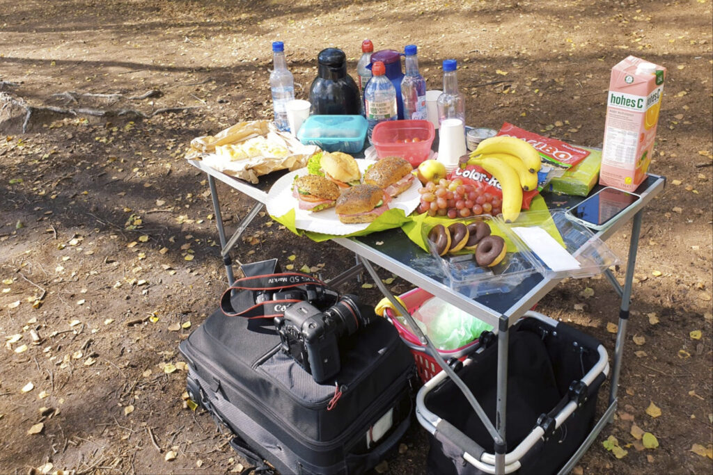 Für ein Fotoshooting in einer Landschaft ist für das Team ein Tisch mit Verpflegung aufgestellt.