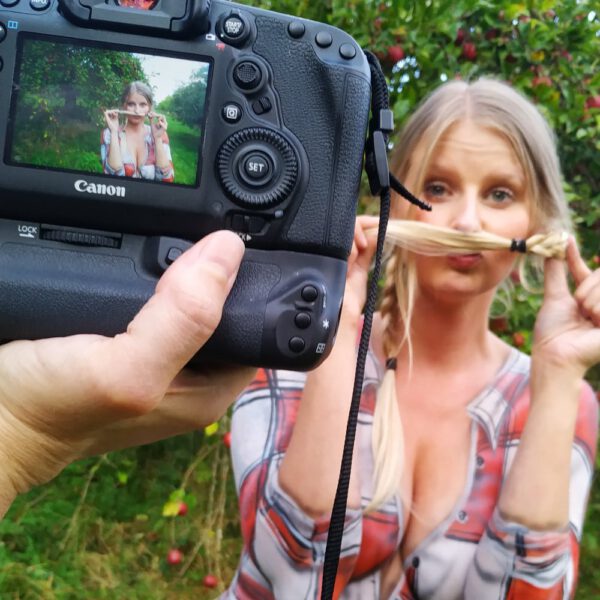 Im Rahmen des Kunstprojektes AGRAR ART hat Bodypaint-Künstler Jörg Düsterwald ein nacktes Fotomodell mit Körperfarbe so bemalt, als hätte die Frau eine kurze blaue Hose und ein rotweiß-kariertes Hemd an. Sie befindet sich in einer Apfelbaumplantage und erntet die Äpfel.