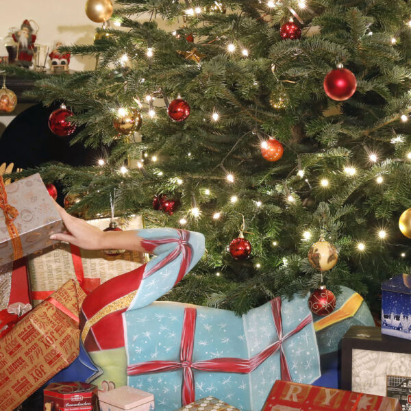 Künstler Jörg Düsterwald hat auf dem Rücken eines Fotomodells die Illusion eines Weihnachtsgeschenks gemalt. Die Frau liegt unter einem geschmückten Weihnachtsbaum, Moderatorin Dany Michalski sitzt daneben und entdeckt überrascht das Paket.