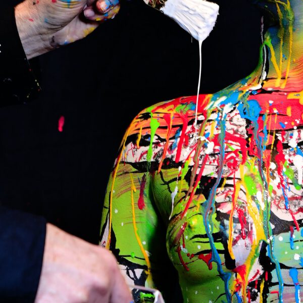 In einer Hamburger Galerie präsentiert Bodyart-Künstler Jörg Düsterwald mit seinem Fotomodell live vor Publikum eine freestyle Kunstperformance. Er versieht sein halbnacktes Modell mit einer Körpermalerei und anschließend bekleckert er die Frau mit viel flüssiger Farbe. Ein Fernsehteam begleitet die Aktion.