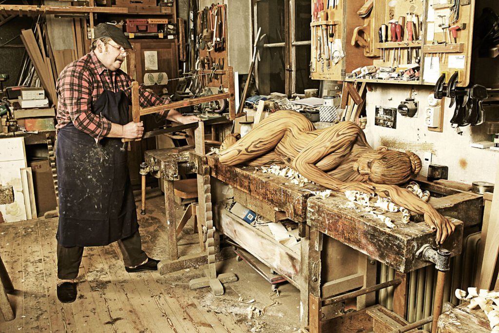 Für das Kunstprojekt WORKING ART, bei dem Berufe mit Bodypaintingmodellen dargestellt werden, hat Künstler Jörg Düsterwald ein Fotomodell vollständig bemalt. Die gestylte Frau sieht aus wie ein Stück Holz und hält sich zusammen mit einem Tischler in seiner Werkstatt auf.