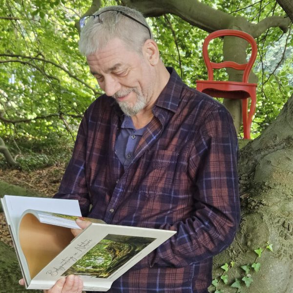Das Buch BODYPAINTING IN NATURE von Künstler Jörg Düsterwald wird mit einem roten Stuhl an einem Originalplatz des Kunstprojektes NATURE ART gezeigt.