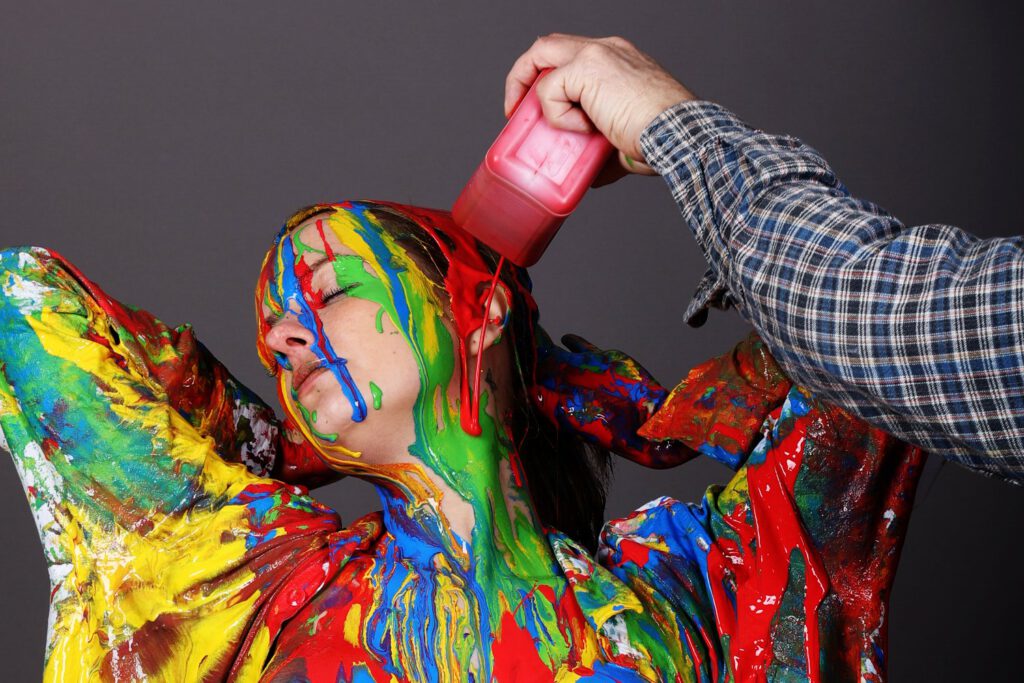 Ein posierendes Fotomodell wurde von Bodyart-Künstler Jörg Düsterwald über Hemd und Hose hinweg mit bunter, flüssiger Farbe übergossen und bekleckert.