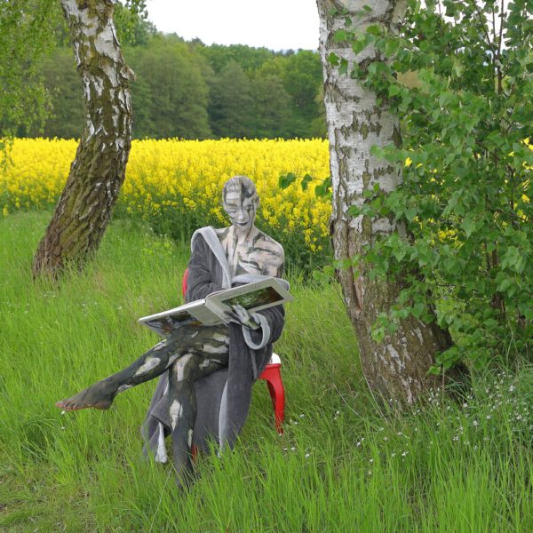 Das Buch BODYPAINTING IN NATURE von Künstler Jörg Düsterwald wird mit einem roten Stuhl an einem Originalplatz des Kunstprojektes NATURE ART gezeigt.