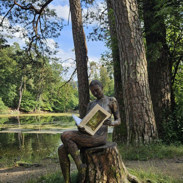 Ein Fotomodell ist mit Farbe der Kulisse angepasst und liest im Buch BODYPAINTING IN NATURE von Künstler Jörg Düsterwald.