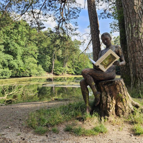 Ein Fotomodell ist mit Farbe der Kulisse angepasst und liest im Buch BODYPAINTING IN NATURE von Künstler Jörg Düsterwald.
