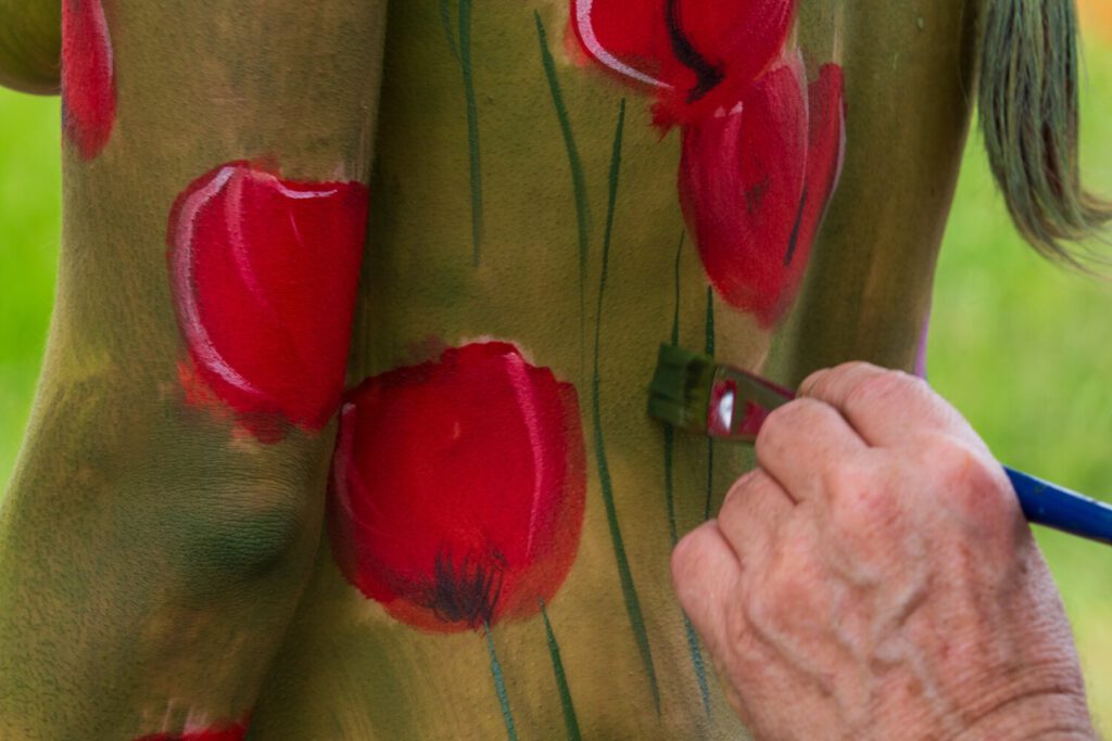 Ein nacktes Fotomodell wird für das Kunstprojekt Natureart von Künstler Jörg Düsterwald vollständig so mit Farbe bemalt, dass die Person mit der Kulisse verschmilzt.
