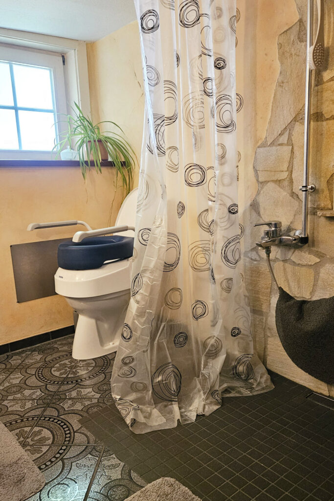 Behindertengerechtes Badezimmer mit bodenebener Dusche und erhöhtem WC.