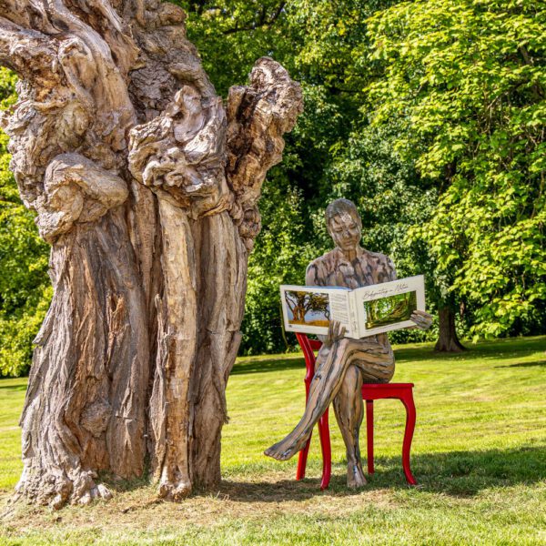 Das Buch BODYPAINTING IN NATURE von Künstler Jörg Düsterwald wird mit einem roten Stuhl an einem Originalplatz des Kunstprojektes NATURE ART gezeigt.
