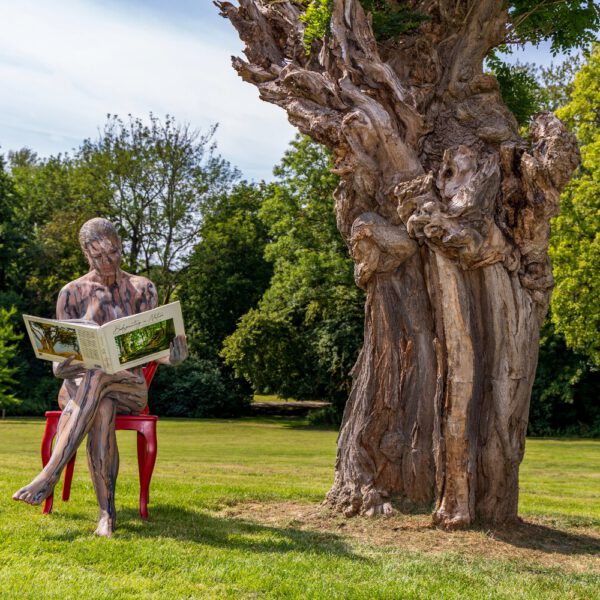 Das Buch BODYPAINTING IN NATURE von Künstler Jörg Düsterwald wird mit einem roten Stuhl an einem Originalplatz des Kunstprojektes NATURE ART gezeigt.