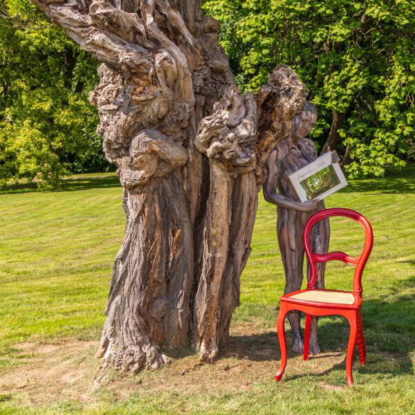 Das Buch BODYPAINTING IN NATURE von Künstler Jörg Düsterwald wird mit einem roten Stuhl an einem Originalplatz des Kunstprojektes NATURE ART gezeigt.