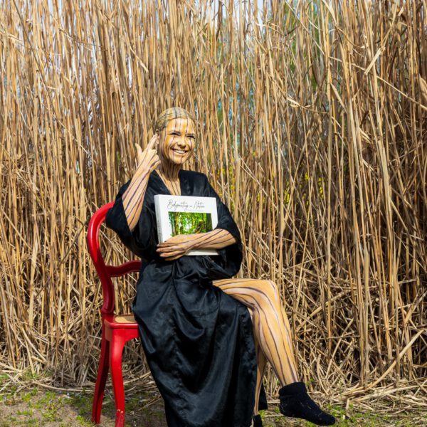 Das Buch BODYPAINTING IN NATURE von Künstler Jörg Düsterwald wird mit einem roten Stuhl an einem Originalplatz des Kunstprojektes NATURE ART gezeigt.