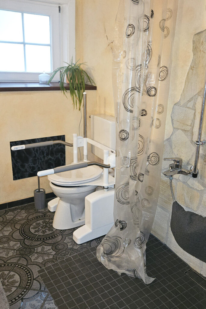 Behindertengerechtes Badezimmer mit bodenebener Dusche und WC-Lifter.